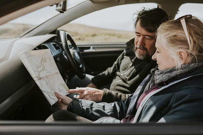 Senior tourist couple looking at the map in the car