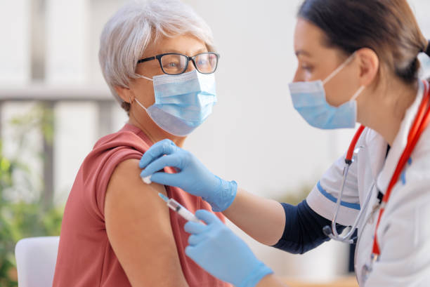 Travel Safety For Senior Travelers - Doctor vaccinating a senior woman. Virus protection. COVID-2019.